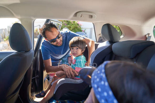 Father fastening toddler son into car seat — Stock Photo