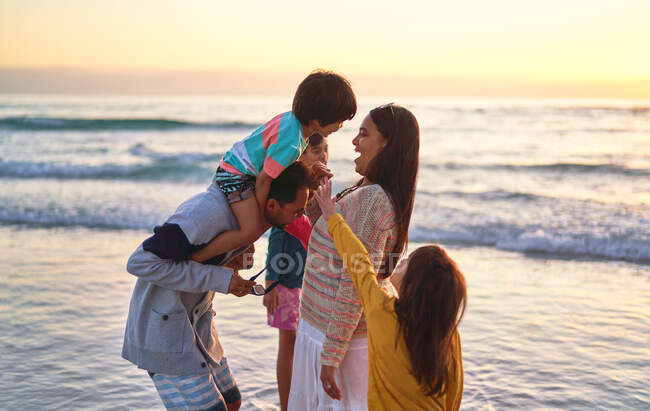 Família feliz vadear no oceano surfar na praia do por do sol — Fotografia de Stock