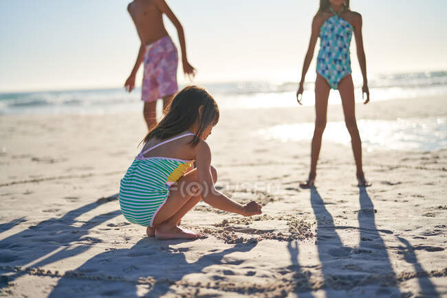 Chica dibujo corazón en la arena en la playa soleada - foto de stock