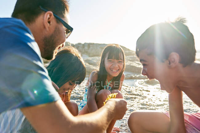 Famille heureuse jouant sur la plage ensoleillée — Photo de stock