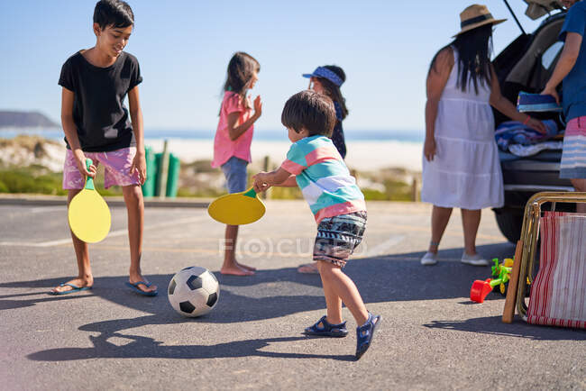Family playing with soccer ball in beach parking lot — Stock Photo