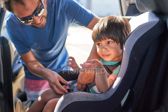 Отец крепления сына в автомобильном кресле — стоковое фото