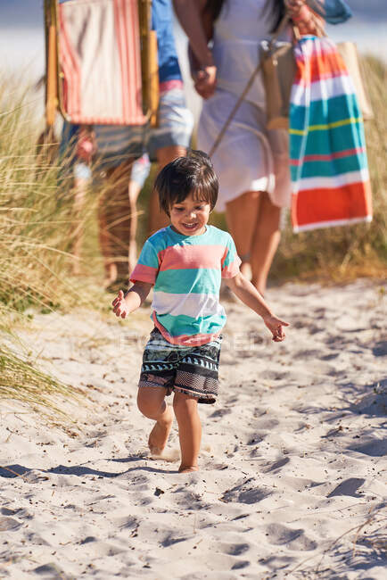 Мальчик бежит по песку на солнечном пляже — стоковое фото