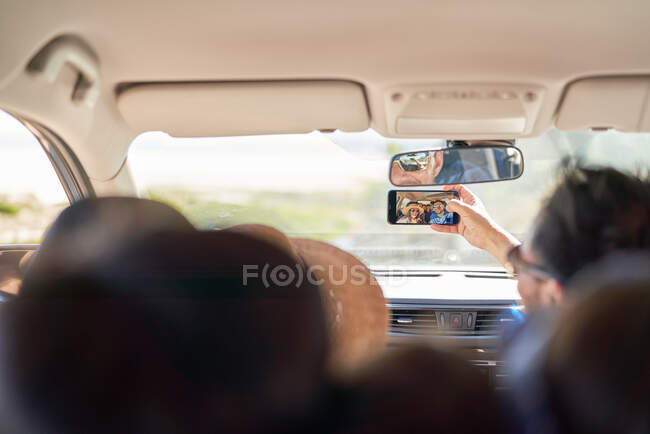 Família tomando selfie com câmera de telefone dentro do carro — Fotografia de Stock