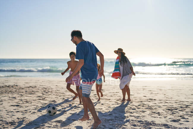 Семья играет в футбол на солнечном пляже океана — стоковое фото