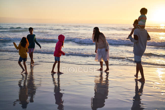 Familia jugando en el océano surf al atardecer - foto de stock
