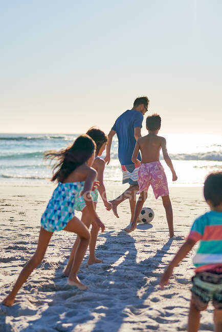 Семья играет в футбол на солнечном пляже океана — стоковое фото