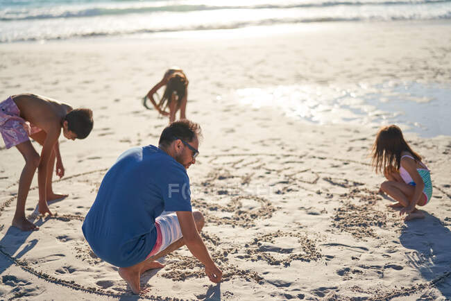 Família desenho na areia na praia ensolarada — Fotografia de Stock