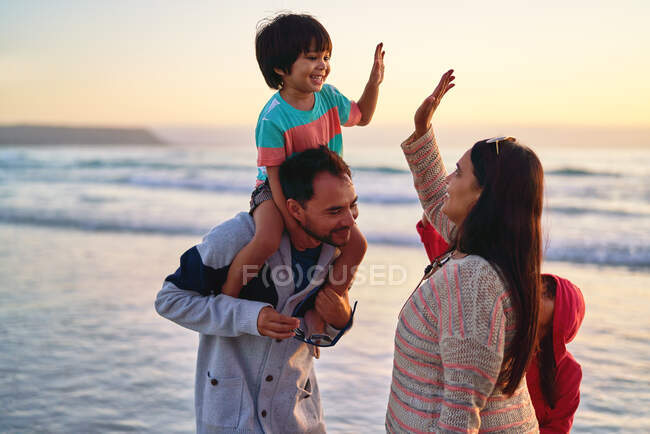 Familia feliz chocando los cinco en la playa del océano - foto de stock