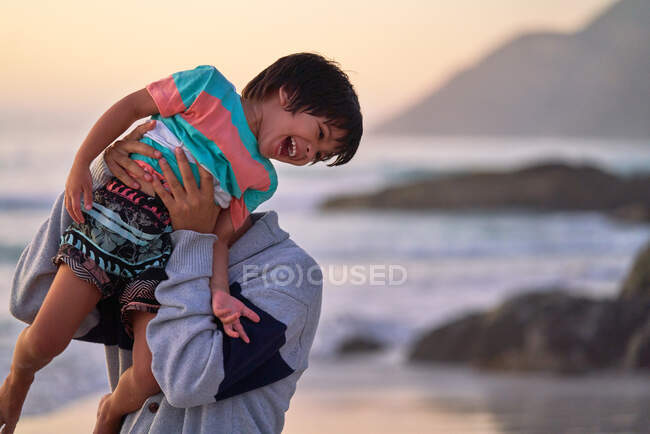 Щасливий батько ліфтинг сміється син на пляжі — стокове фото
