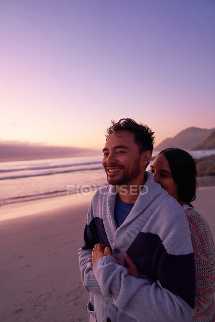 Casal afetuoso abraçando na praia do oceano ao pôr do sol — Fotografia de Stock
