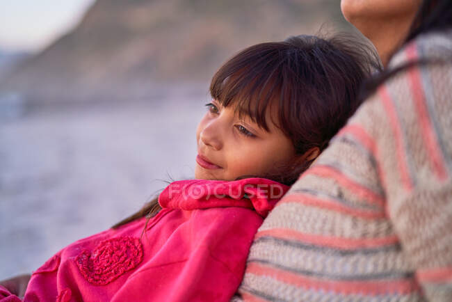 Serena menina inclinada na mãe na praia — Fotografia de Stock