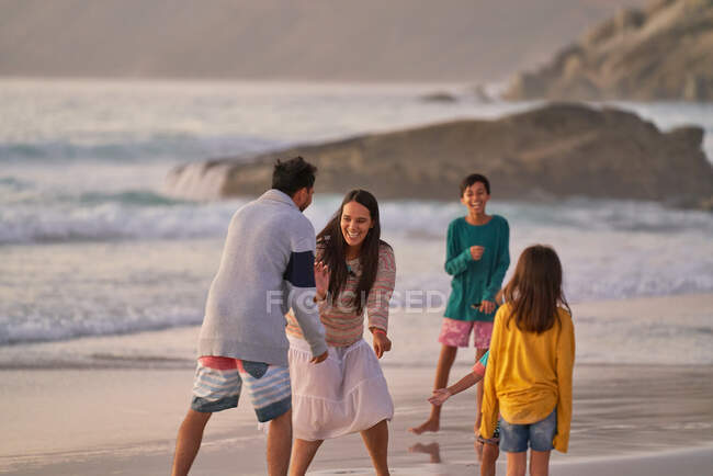 Familia feliz jugando en la playa del océano - foto de stock