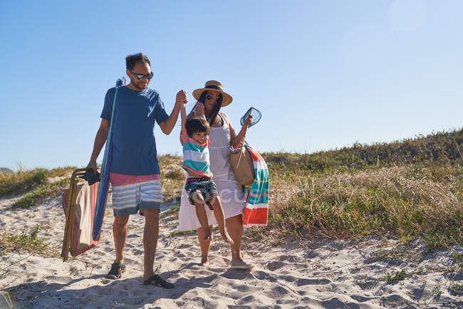 Игривая семья, прогуливающаяся по песку на солнечном пляже — стоковое фото