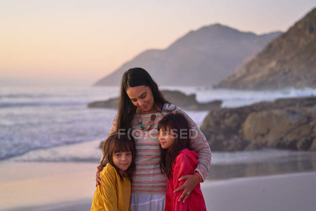 Affectionate mother and daughters hugging on beach — Stock Photo