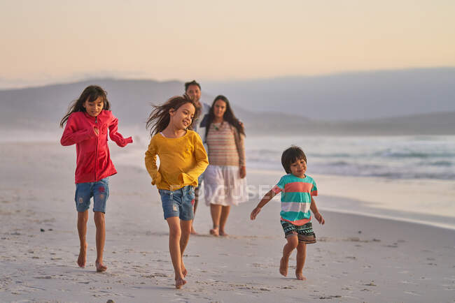 Familia feliz corriendo en la playa del océano - foto de stock