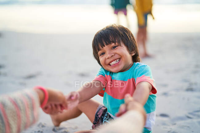 Щасливий хлопчик тримає руки з матір'ю на пляжі — стокове фото