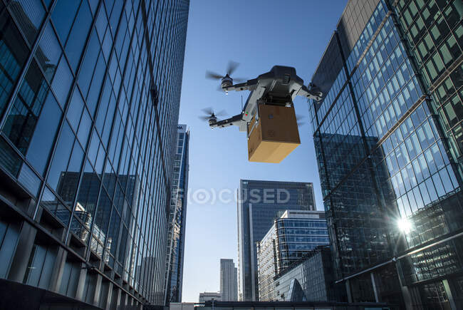 Drone delivering package between highrise buildings, London, UK — Stock Photo