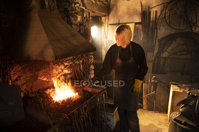 Female blacksmith working at foundry flame — Stock Photo