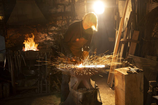 Female blacksmith working in workshop — Stock Photo