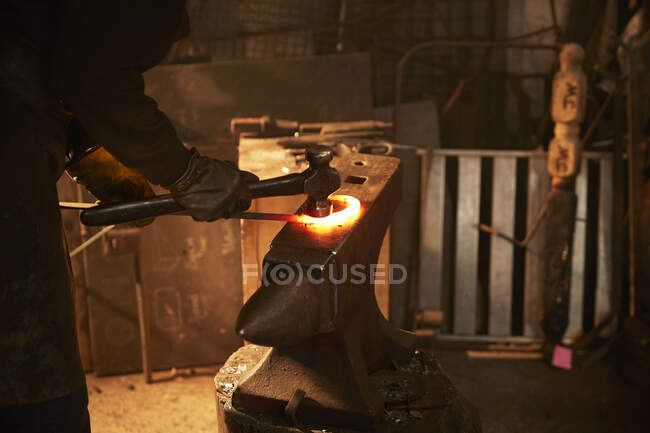 Кузнец формирует сталь на наковальне в мастерской — стоковое фото