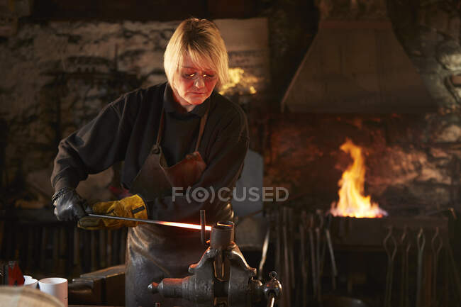 Female blacksmith working in workshop — Stock Photo