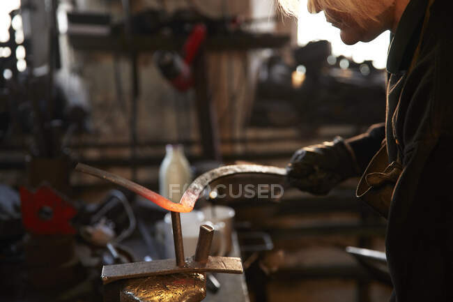 Female blacksmith shaping steel in workshop — Stock Photo