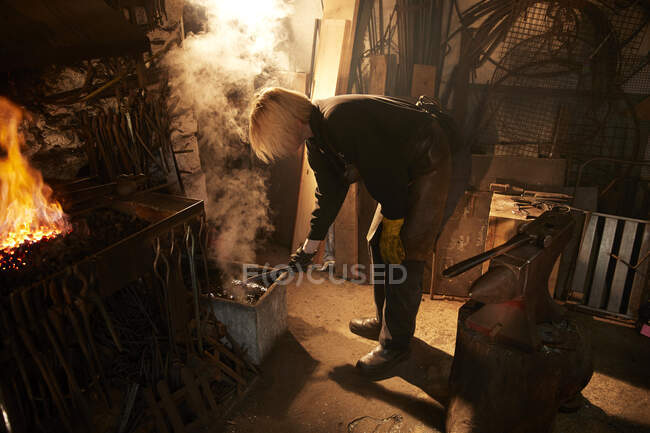 Forgeron féminin travaillant en atelier — Photo de stock