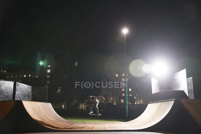 Jeune homme skateboard sur la rampe au skate park la nuit — Photo de stock
