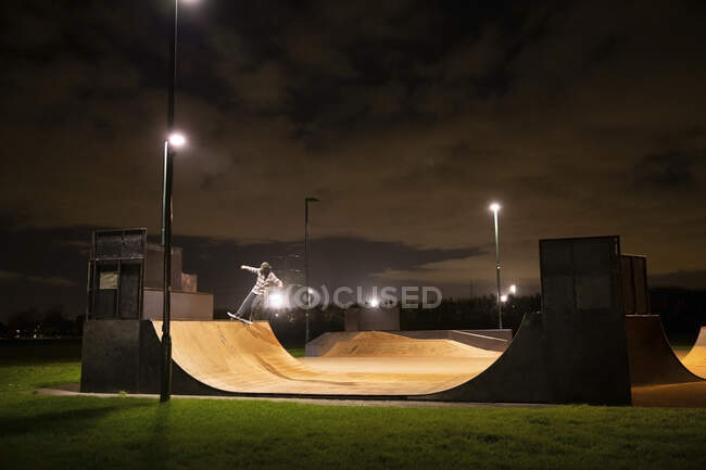 Jeune homme skateboard sur rampe de skate park la nuit — Photo de stock
