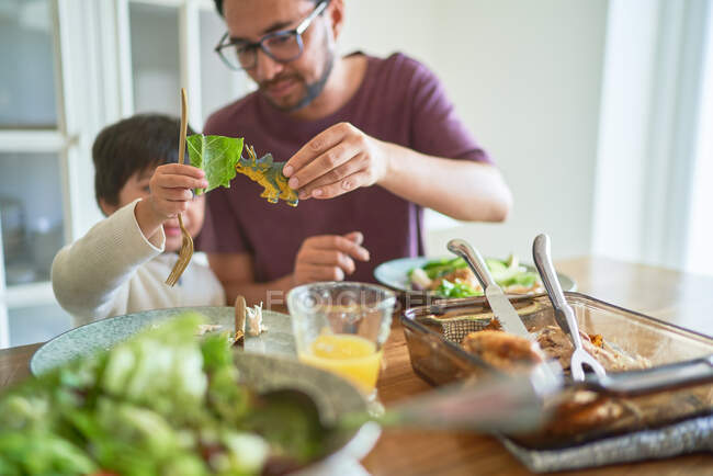 Playful father and son eating with toy dinosaur — Stock Photo