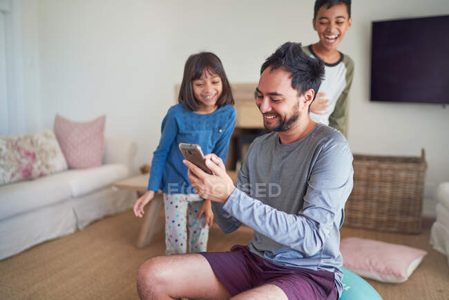 Щасливий батько і діти зі смартфоном у вітальні — стокове фото