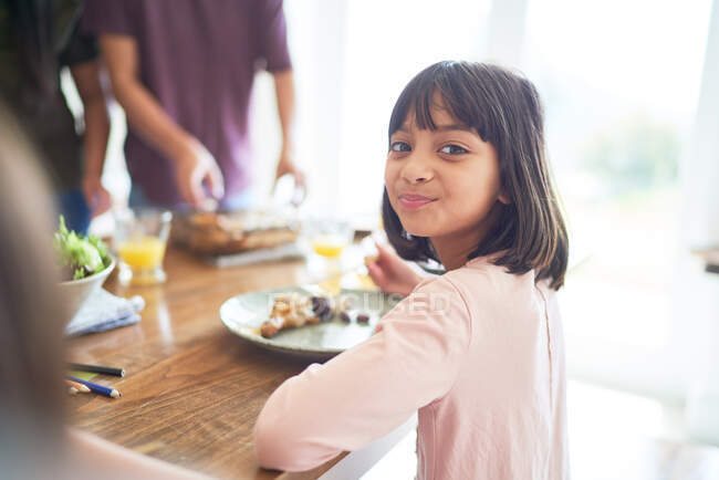 Retrato chica feliz almorzando con la familia en la mesa - foto de stock
