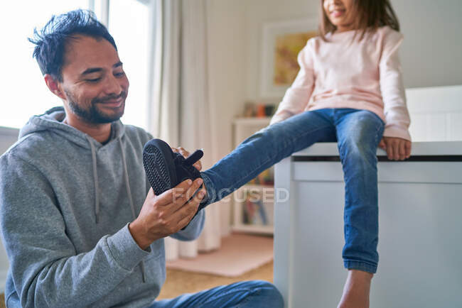 Отец помогает дочери обуться. — стоковое фото
