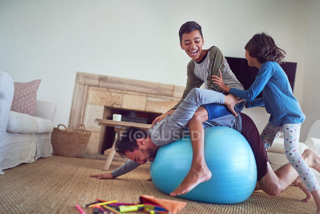Felice famiglia che gioca sulla palla fitness in soggiorno — Foto stock