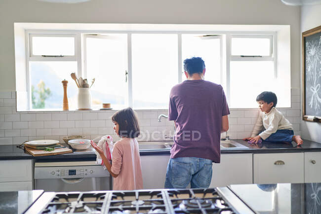 Familia haciendo platos en el fregadero de cocina - foto de stock