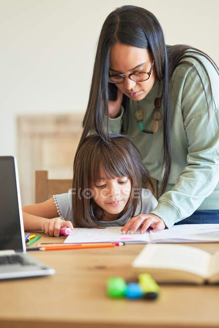 Madre ayudando a su hija con la tarea - foto de stock