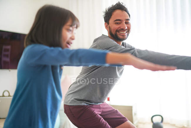Happy father and daughter exercising in living room — Stock Photo