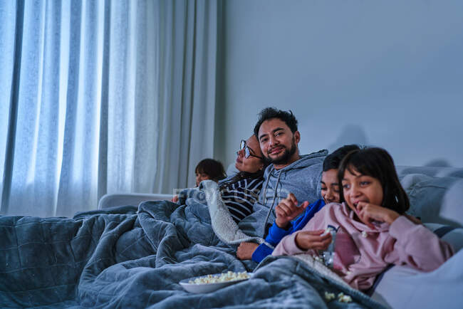 Retrato homem feliz relaxando e assistindo filme com a família no sofá — Fotografia de Stock