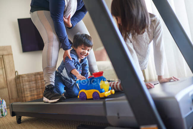 Happy mother and kids with toys on treadmill — Stock Photo