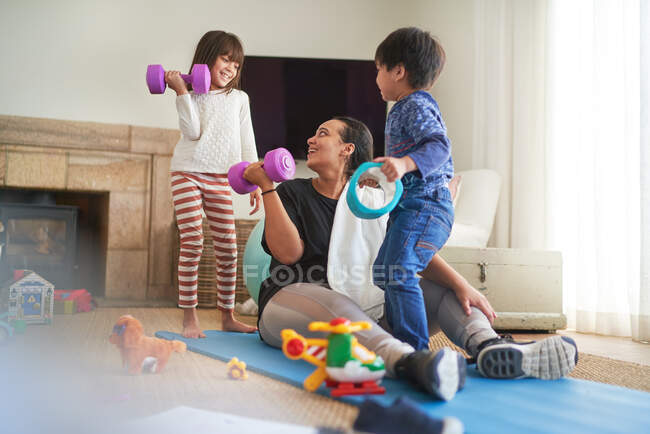 Madre e hijos haciendo ejercicio en la sala de estar - foto de stock