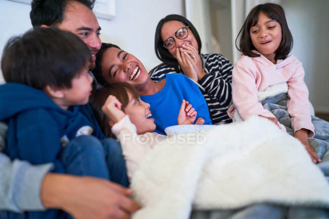 Familia feliz riendo en el sofá - foto de stock