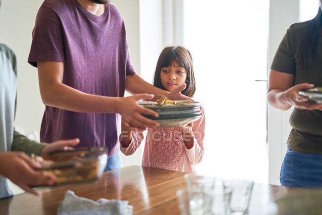 Familie räumt Geschirr vom Esstisch — Stockfoto