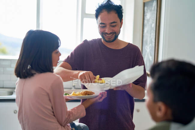 Pai feliz alimentando filha comida de takeout na cozinha — Fotografia de Stock