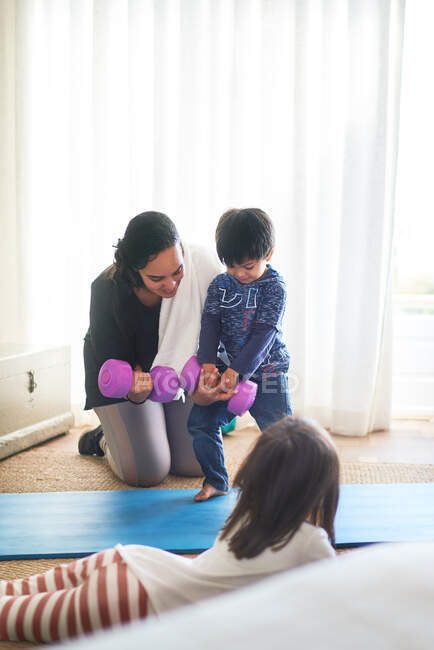 Mother and kids exercising with dumbbells in living room — Stock Photo