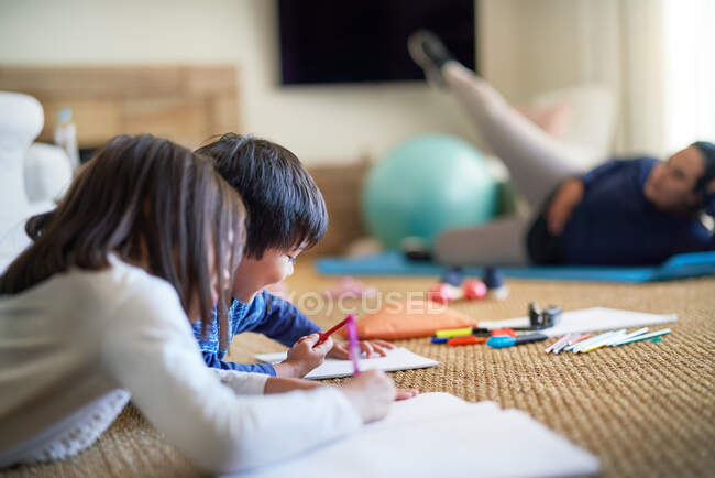 Crianças colorir no chão perto da mãe exercitando — Fotografia de Stock