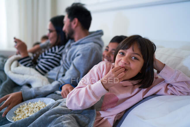 Retrato menina feliz comer pipocas no sofá — Fotografia de Stock