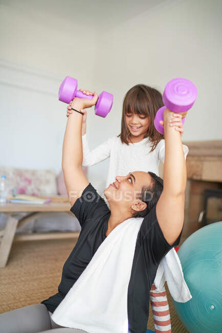 Hija ayudando a la madre a hacer ejercicio con pesas - foto de stock