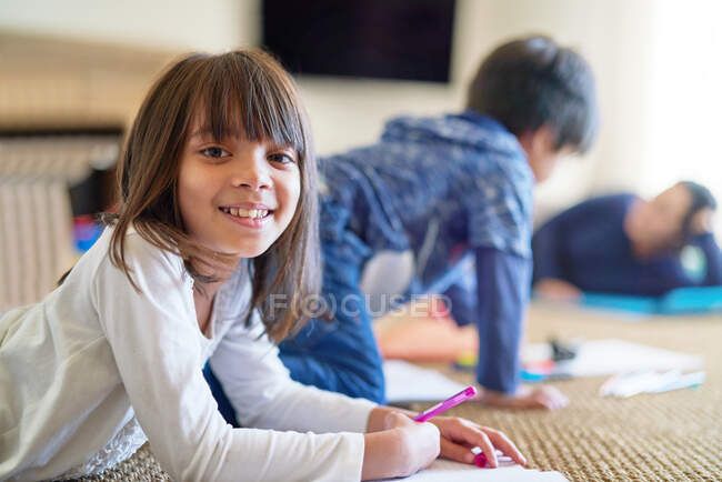 Portrait happy girl coloring on floor — Stock Photo