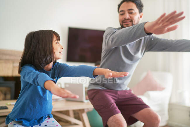 Father and daughter exercising doing squats in living room — Stock Photo